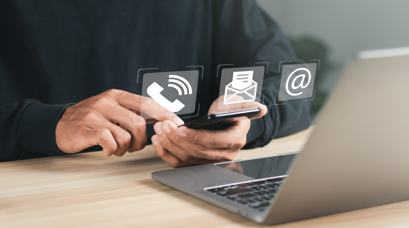 Person using smartphone with contact icons displayed, representing customer support
